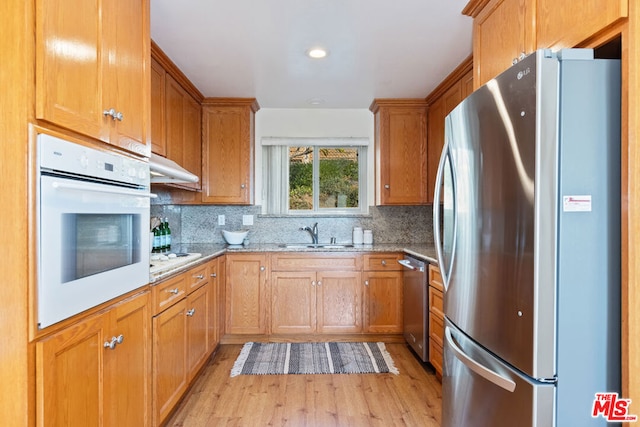 kitchen featuring light stone countertops, sink, decorative backsplash, and stainless steel appliances