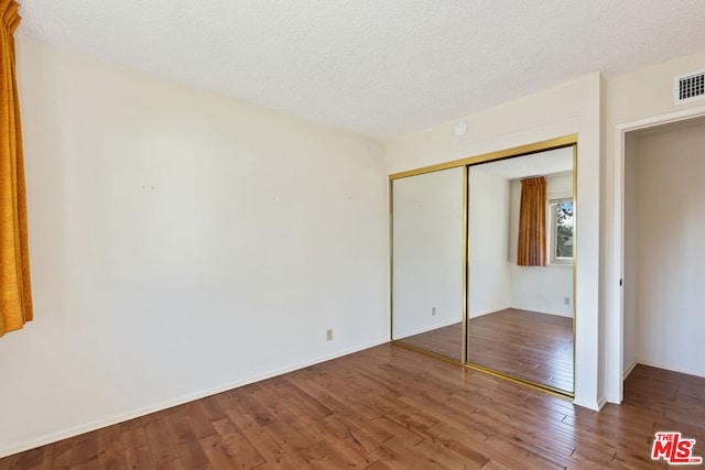 unfurnished bedroom with a closet, hardwood / wood-style flooring, and a textured ceiling