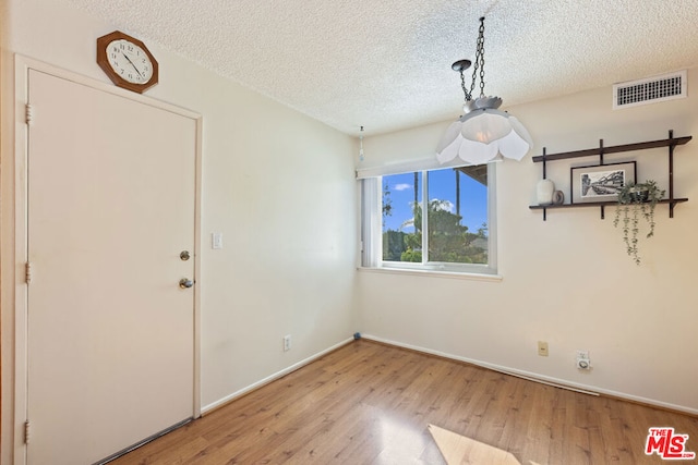 unfurnished dining area with hardwood / wood-style flooring and a textured ceiling