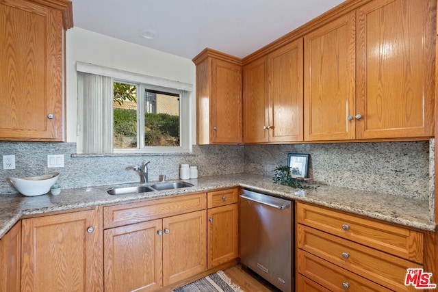 kitchen with light stone counters, sink, stainless steel dishwasher, and tasteful backsplash