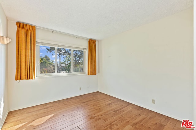 unfurnished room with light hardwood / wood-style floors and a textured ceiling