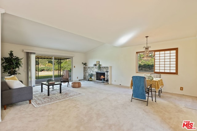 living room with carpet floors, a notable chandelier, lofted ceiling, and a stone fireplace