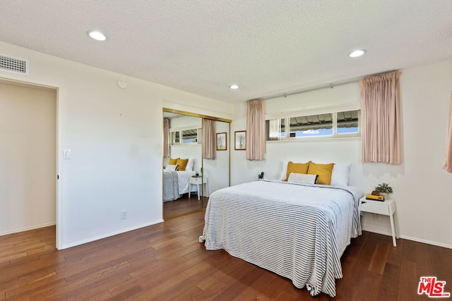 bedroom with a textured ceiling, a closet, and dark hardwood / wood-style flooring