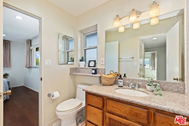 bathroom with hardwood / wood-style flooring, plenty of natural light, toilet, and vanity