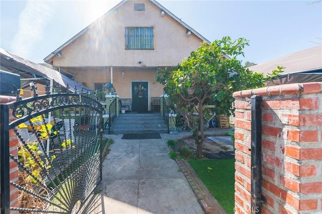 view of front of home with a gate and stucco siding