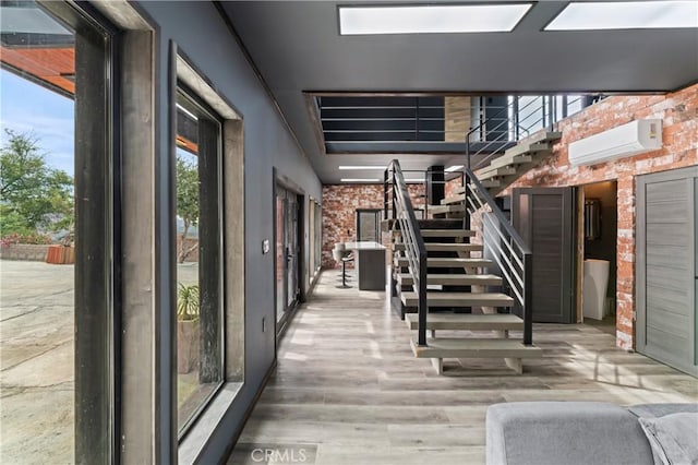 stairs with wood-type flooring, an AC wall unit, and brick wall