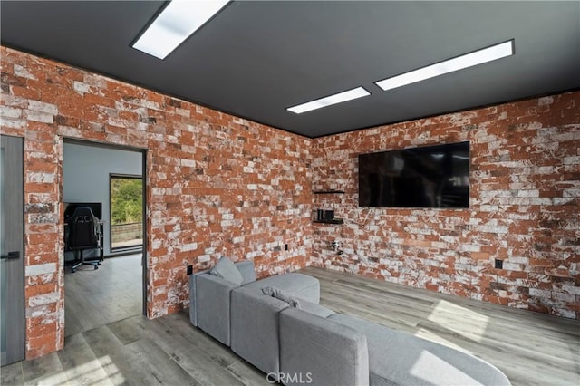 living room with brick wall and light hardwood / wood-style flooring