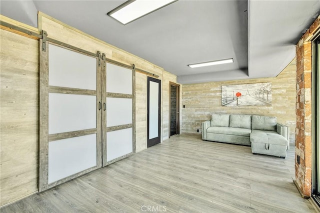 interior space with hardwood / wood-style flooring, a barn door, and wooden walls