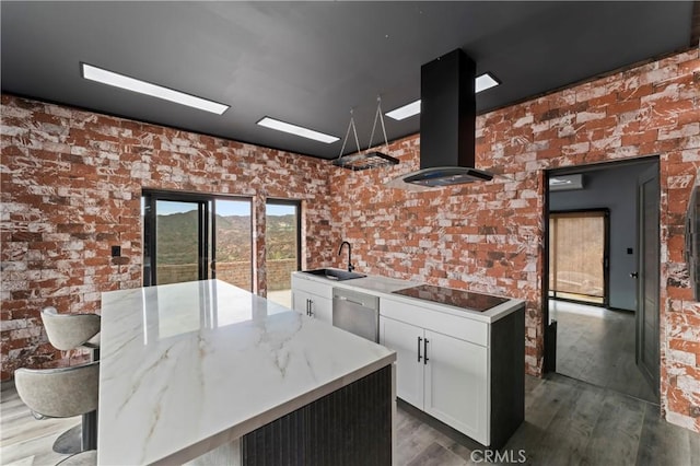 kitchen featuring stainless steel dishwasher, white cabinets, light stone counters, a center island, and range hood