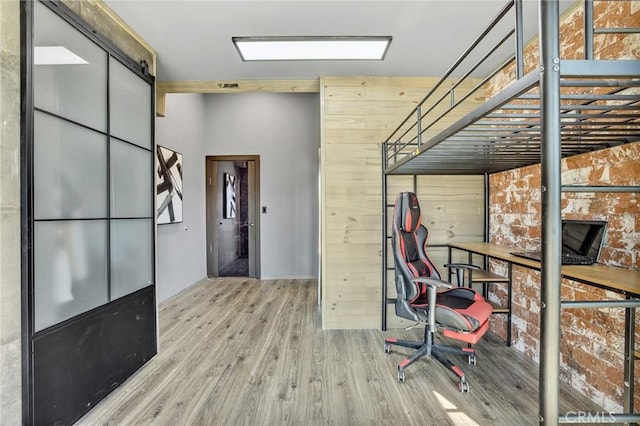 hallway featuring light hardwood / wood-style floors, wood walls, and a barn door