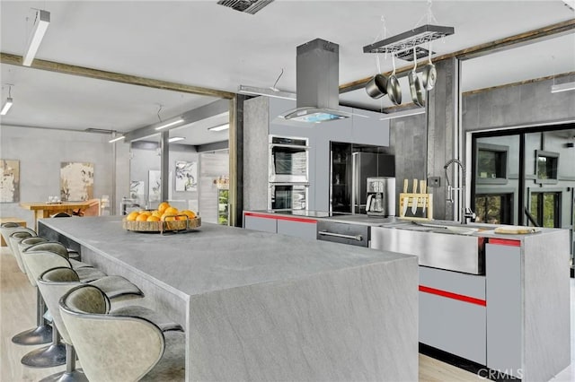 kitchen featuring light hardwood / wood-style floors, white cabinets, a kitchen island, sink, and double oven