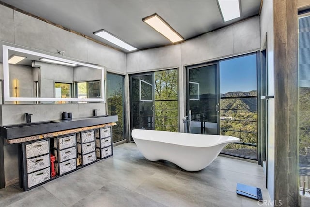 bathroom featuring a bath, vanity, and concrete flooring