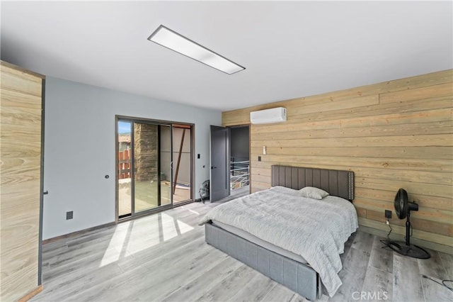 bedroom featuring wood walls, light hardwood / wood-style flooring, access to outside, and a wall mounted AC