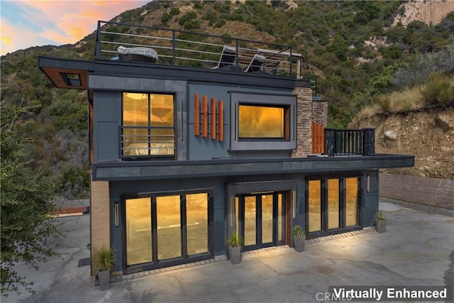 back house at dusk featuring a patio area