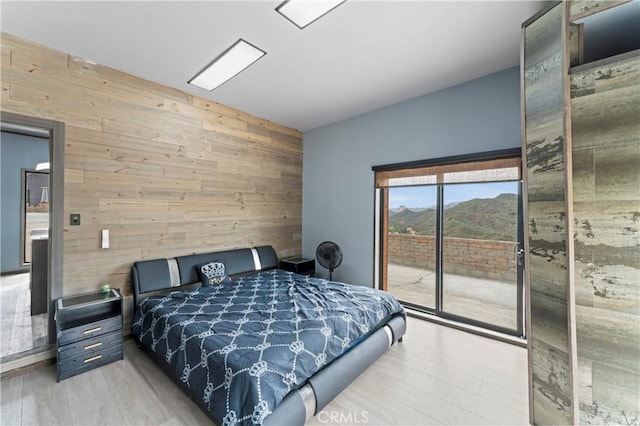 bedroom with wood walls, light hardwood / wood-style flooring, and access to outside