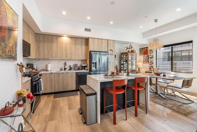 kitchen with black appliances, a kitchen island, light hardwood / wood-style floors, sink, and a notable chandelier