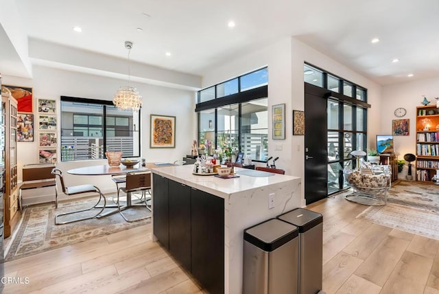 kitchen with light wood-type flooring, pendant lighting, a center island, and an inviting chandelier