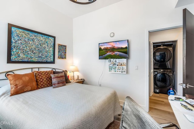 bedroom with hardwood / wood-style flooring and stacked washing maching and dryer