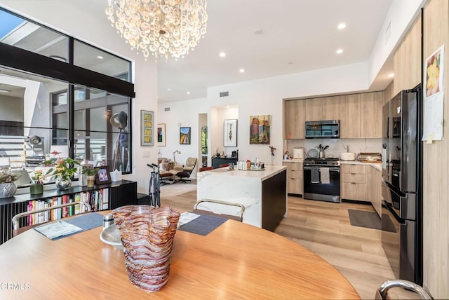 dining area with light wood-type flooring and a notable chandelier