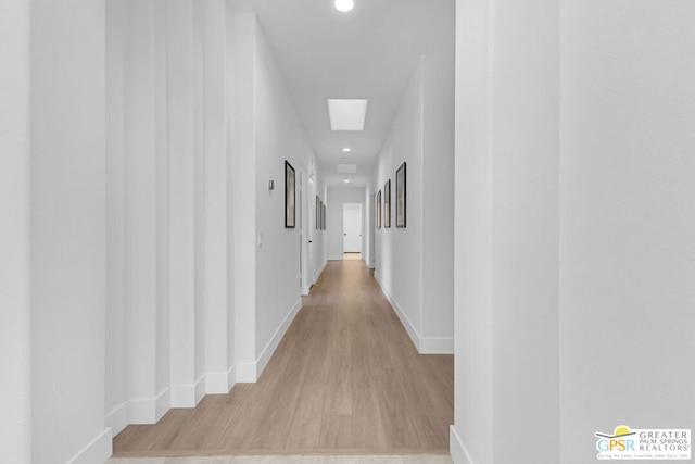 hallway featuring a skylight and light hardwood / wood-style floors