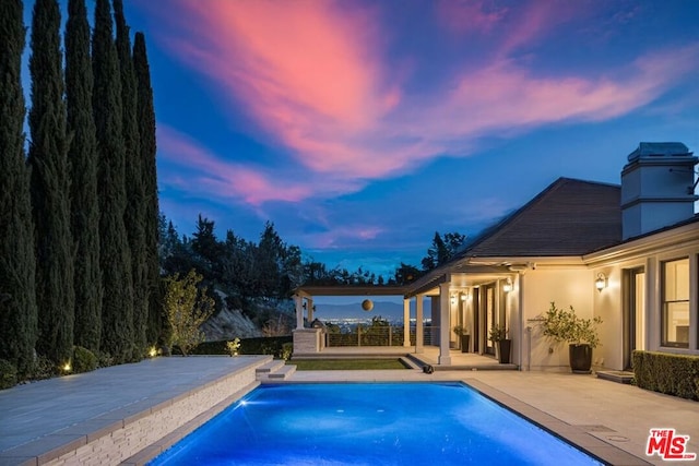 pool at dusk with a patio area