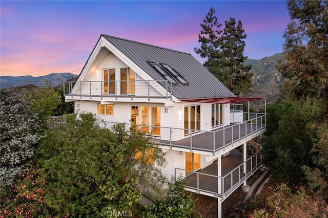 back house at dusk featuring a balcony and a mountain view