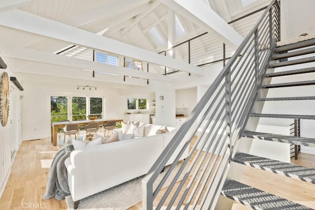 living room featuring beam ceiling, high vaulted ceiling, and light wood-type flooring