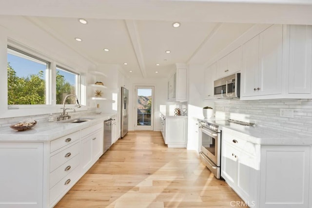 kitchen featuring appliances with stainless steel finishes, sink, a wealth of natural light, and white cabinets