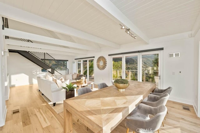 dining room featuring beam ceiling and light wood-type flooring