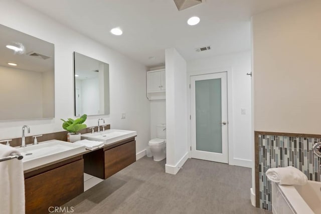 bathroom featuring vanity, toilet, and a tub