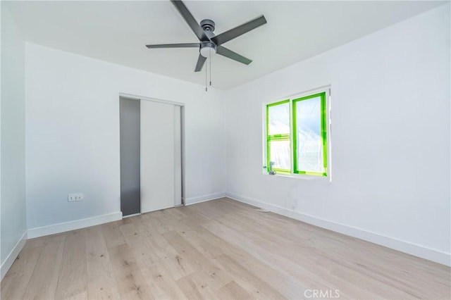 empty room with ceiling fan and light hardwood / wood-style flooring