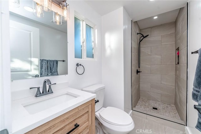 bathroom featuring vanity, toilet, tile patterned floors, and a tile shower