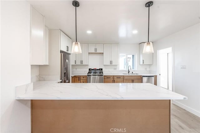 kitchen with pendant lighting, white cabinetry, appliances with stainless steel finishes, and kitchen peninsula