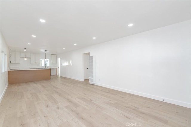 unfurnished living room with sink and light hardwood / wood-style flooring