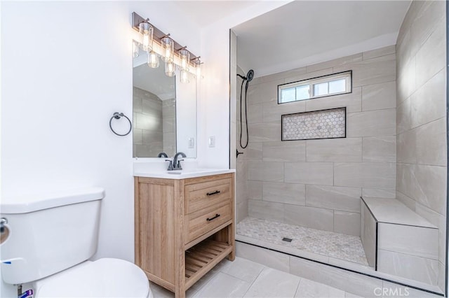 bathroom featuring a tile shower, toilet, tile patterned floors, and vanity