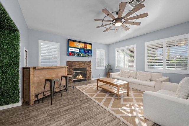 living room featuring ceiling fan and a stone fireplace