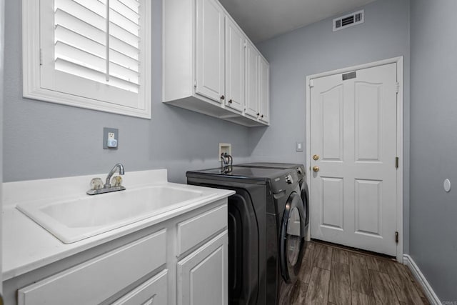 laundry area featuring sink, cabinets, dark wood-type flooring, and washer and clothes dryer