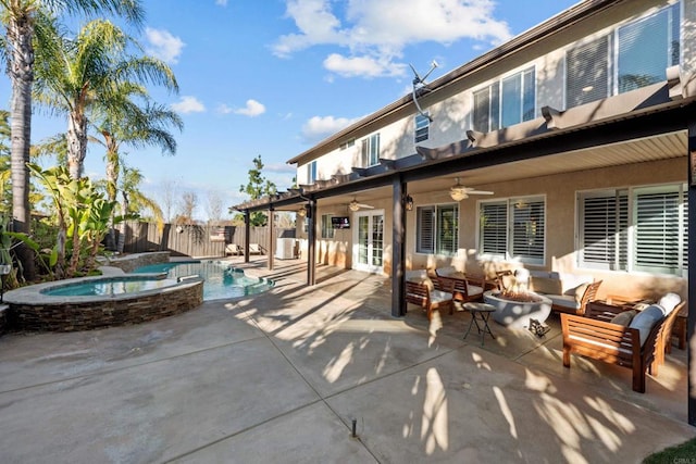 rear view of property featuring a patio, ceiling fan, a swimming pool with hot tub, and an outdoor living space with a fire pit