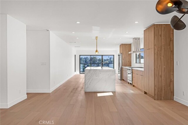 kitchen with a center island, decorative light fixtures, high end appliances, light hardwood / wood-style floors, and island range hood