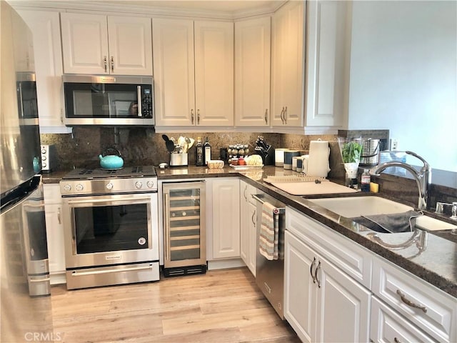 24400 Alta Vista Dr, Dana Point, CA 92629 - kitchen with wine cooler, appliances with stainless steel finishes, white cabinets, tasteful backsplash, and light wood finished floors