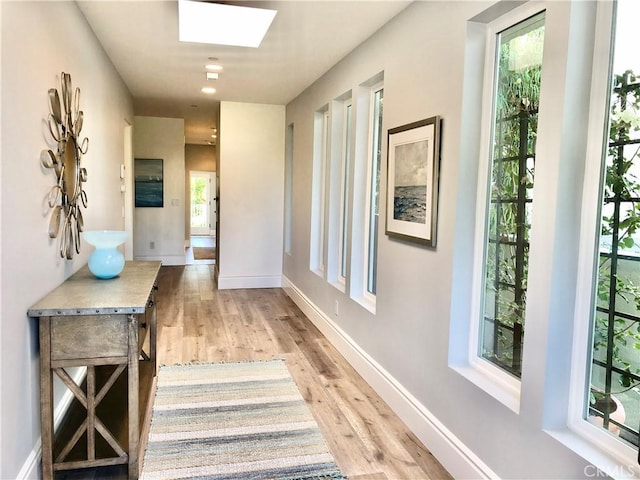 hallway featuring a skylight and light hardwood / wood-style floors