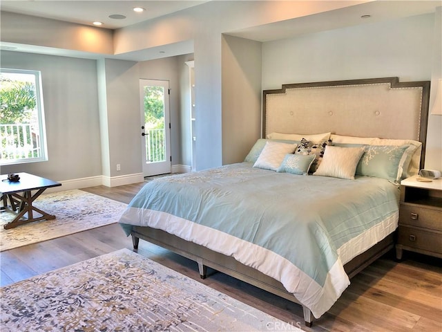 bedroom featuring hardwood / wood-style floors, multiple windows, and access to exterior