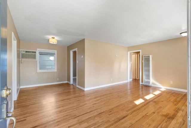 unfurnished room featuring light wood-type flooring and an AC wall unit