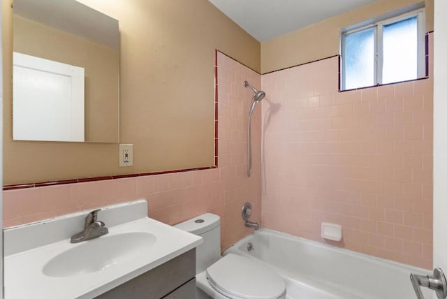 full bathroom featuring toilet, tile walls, decorative backsplash, vanity, and tiled shower / bath