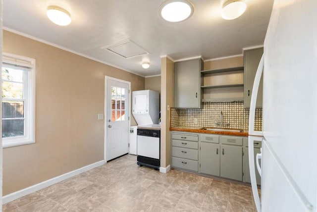 kitchen featuring white appliances, a wealth of natural light, stacked washer and dryer, tasteful backsplash, and sink