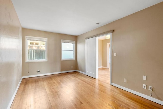 unfurnished room with a barn door and light hardwood / wood-style flooring