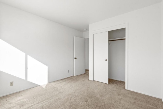 unfurnished bedroom with light colored carpet and a closet