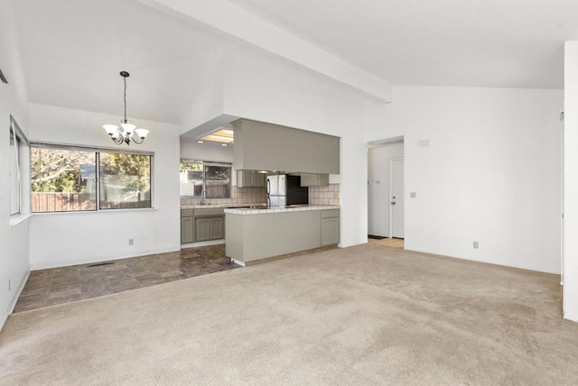 unfurnished living room featuring light carpet, sink, a chandelier, and vaulted ceiling