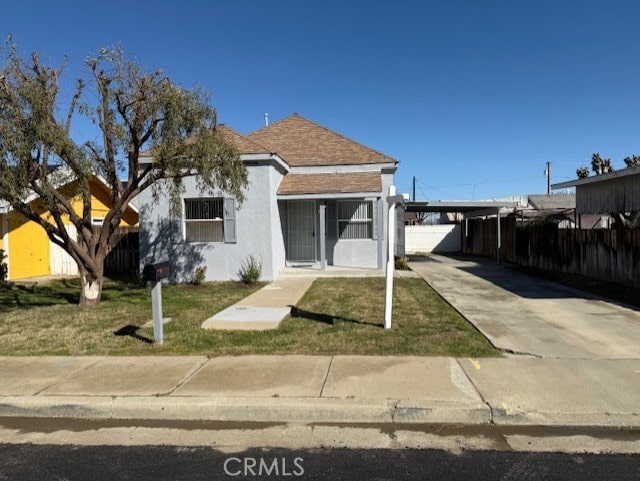 bungalow-style house with an attached carport, fence, stucco siding, a front lawn, and concrete driveway