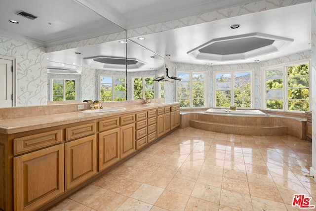 bathroom with ornamental molding, vanity, and tiled tub